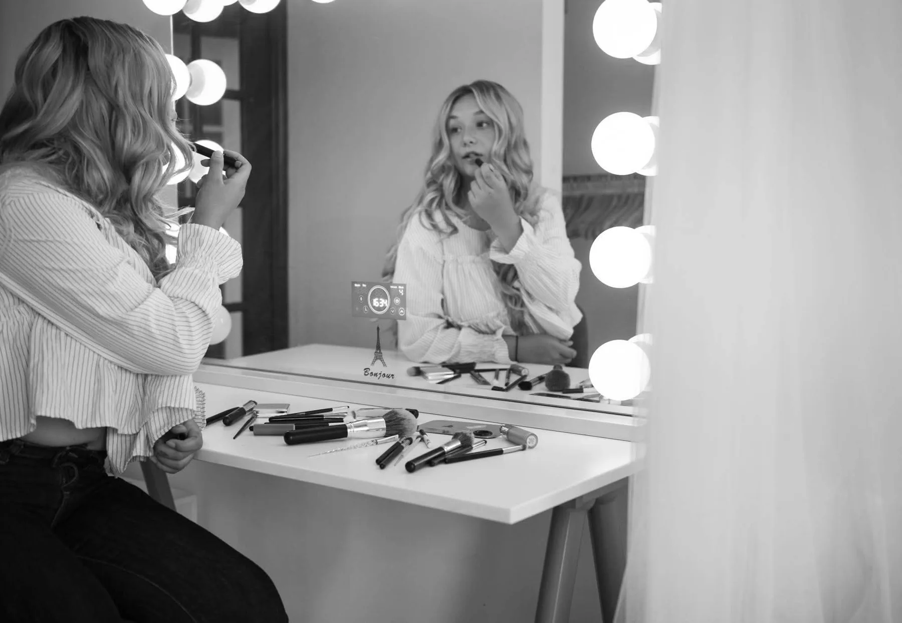 Marisa preparing makeup at a lighted mirror